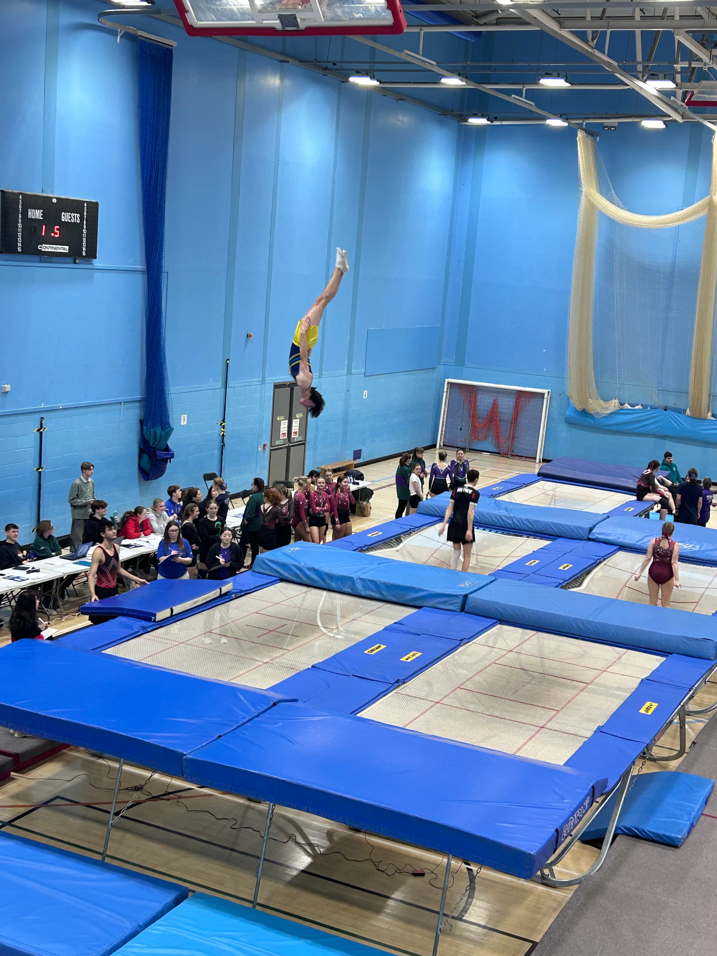 An athlete inverted high above a trampoline during a competition